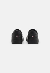 Zapatillas de cuero negro con un acabado suave, puntera redonda, cuello acolchado y un pequeño detalle de logo de color en el talón. Suela de goma.