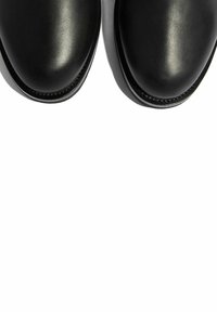 Czarne skórzane buty o gładkim wykończeniu, z okrągłym noskiem i kontrastowym przeszyciem wzdłuż podeszwy. Minimalistyczny design bez ozdób.