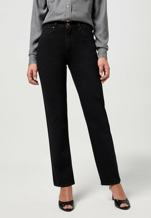 Black denim straight-leg jeans with a high waist, featuring a front button closure and stitched pockets. Worn with a gray button-up shirt and heels.