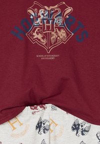 Maroon top with Hogwarts crest and "School of Witchcraft and Wizardry" text, paired with light shorts featuring Hogwarts house symbols and names.