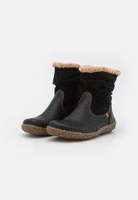 Zwarte enkellaarzen met bruine rubberen zolen, zijrits en zachte tan fleecevoering zichtbaar aan de bovenrand.