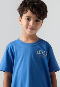 Modrá bavlněná trička s krátkým rukávem, prezentující bílé logo "LEVI'S 1873" na hrudi. Hladká textura, kulatý výstřih.