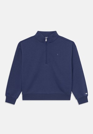 Tamsiai mėlynas megztinis su ketvirčio užtrauktuku, raukšlėtais rankogaliais ir apykakle, su mažu logotipu krūtinėje ir lygiu audinio paviršiumi.