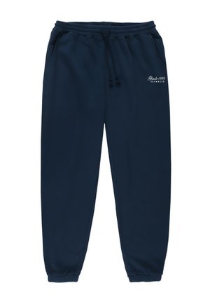 Granatowe spodnie dresowe z elastycznym pasem, sznurkiem, dwoma bocznymi kieszeniami i ściągaczami na kostkach. Mały biały napis na lewym udzie.