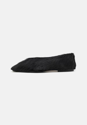Black faux fur flat shoe with a pointed toe and low profile. Textured surface and smooth sole. Minimalistic design.
