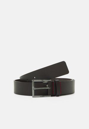 Zwarte leren riem met een rechthoekige zilveren gesp, voorzien van rode stiksels en een gladde textuur. Lengte verstelbaar met meerdere gaatjes.