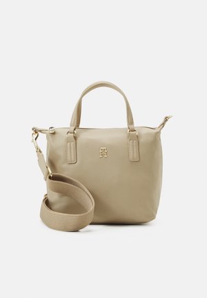 Beige leren handtas met dubbele handvatten, goudkleurig beslag en een afneembare brede beige schouderriem, getoond op een witte achtergrond.