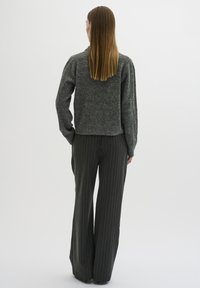 Grey wool sweater with a cropped design, paired with wide-leg pinstriped trousers in dark grey. Texture appears soft and cozy.