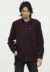 Bordeaux lange mouwen shirt van textured stof, met een button-down kraag, twee borstzakken en een klein rood logo detail.