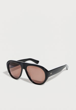 Black aviator-style sunglasses with pink-tinted lenses and slim arms resting on a white surface.