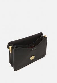 Pochette en cuir noir avec un design ondulé, quincaillerie dorée et fermeture à pression magnétique, comportant un compartiment intérieur.