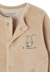 Beige Babystrampler mit Druckknöpfen, der ein lächelndes Eichhörnchen mit einer Eichel und dem französischen Text "à croquer" auf der Brust zeigt.