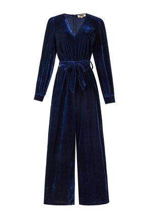 Donkerblauw fluwelen jumpsuit met lange mouwen, diepe V-hals, taillekoord en wijd uitlopende pijpen. Zachte textuur met subtiele glans.