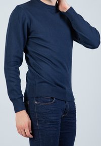 Marineblauer Pullover aus weich gestricktem Material, mit Rundhalsausschnitt, langen Ärmeln sowie gerippten Bündchen und Saum für eine taillierte Passform.