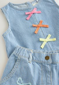 Hihaton sinivalkoraidallinen denimmekko, jossa on vaaleanpunaisia, oransseja ja keltaisia kangasrusetti rintamuksessa ja napillinen suljenta.
