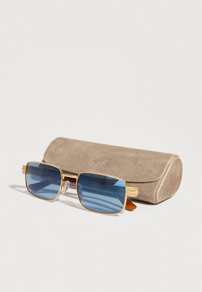 Guldindrammede rektangulære solbriller med blå linser foran et beige beskyttelsesetui af ruskind på hvid baggrund.