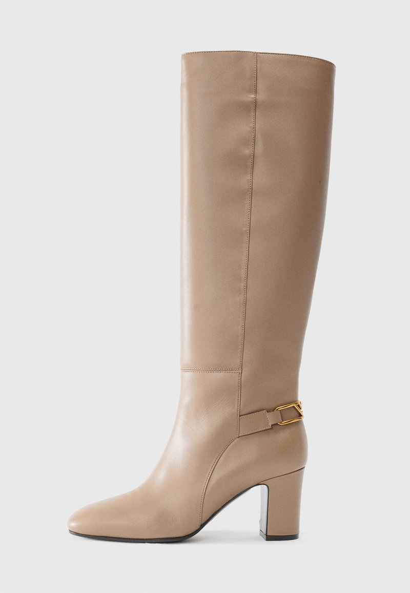 Beige leather knee-high boot with a pointed toe, structured shape, and a gold-tone buckle accent on the side, featuring a block heel.
