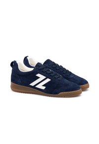 Marineblaue Wildleder-Sneaker mit weißem Logo und Schnürsenkeln, ausgestattet mit einer Gummisohle. Niedrig geschnittenes Design mit einer strukturierten Oberseite.