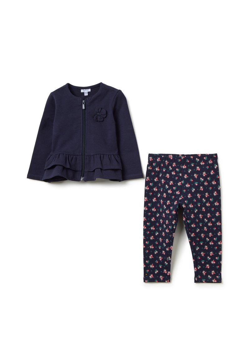 Marineblaues Reißverschluss-Jackett mit Peplum-Saum und floralem Akzent, kombiniert mit marineblauen Leggings, die über ein kleines rosa und weißes Blumenmuster verfügen.