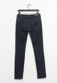 Mörkblå denim skinny jeans på en svart galge, med bakfickor och subtila sömnadsdetaljer. Slät textur, slim fit-design.