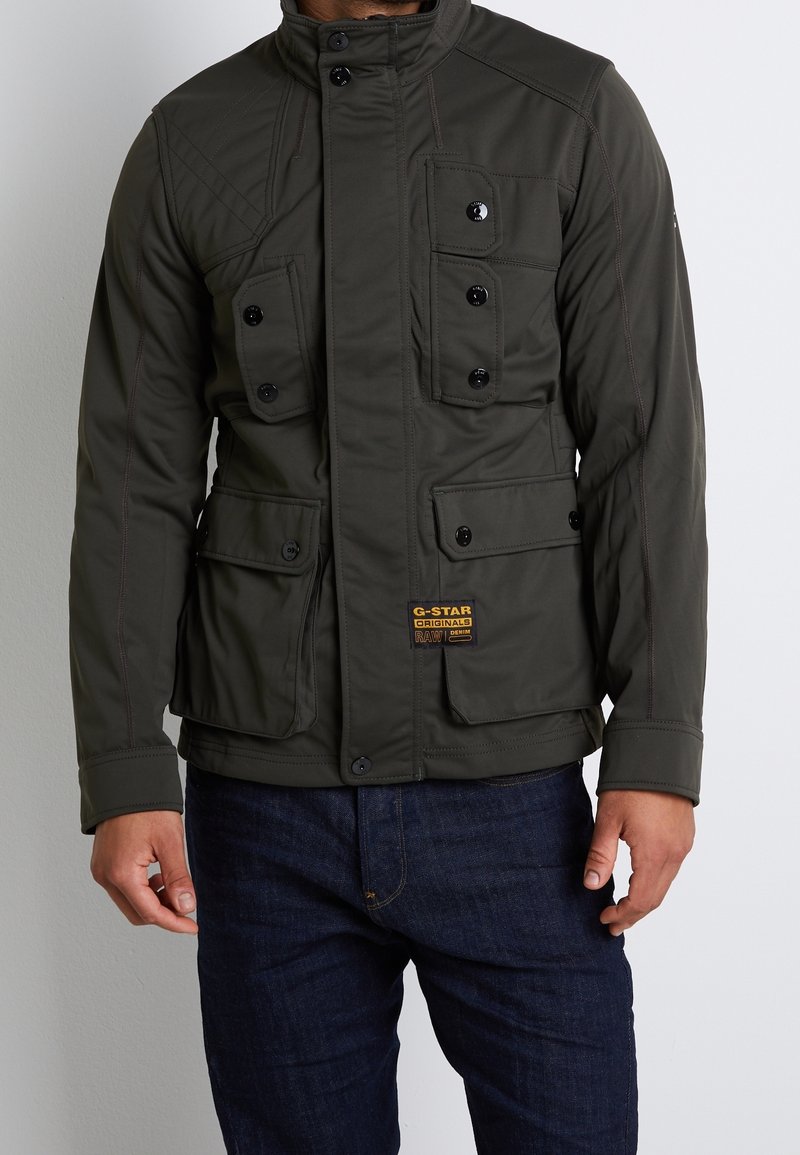 Ciemnozielona pikowana kurtka z czterema kieszeniami z przodu, zapięciem na guziki i wysokim kołnierzem. Zawiera kontrastowe przeszycia oraz naszywkę z logo.