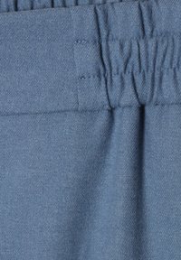 Blauwe stof met een gestructureerd oppervlak en een gather-elastische tailleband. Het materiaal lijkt zacht met een lichte glans en een lichte afwerking.