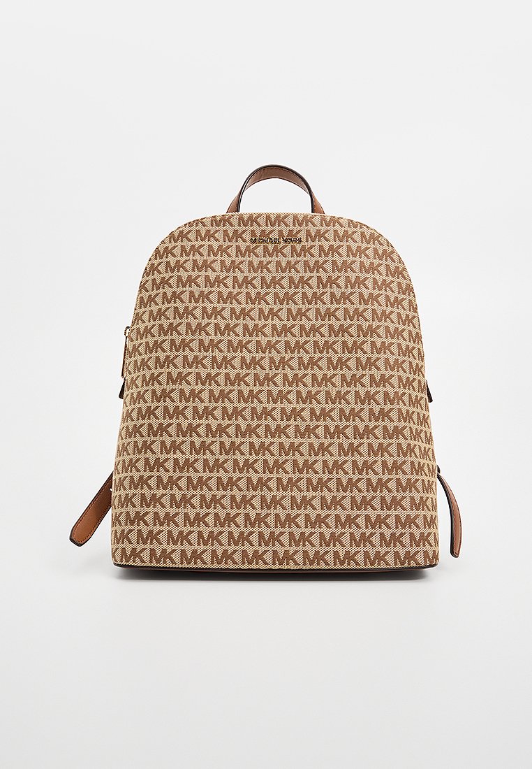 Zaino color tan con un motivo a monogramma MK ripetuto, forma arrotondata, dettagli in pelle marrone e manico superiore per il trasporto.