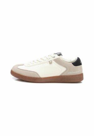 Zapatillas con una parte superior de ante beige y cuero blanco, acento negro en el talón y suela de goma marrón. Presentan cierre de cordones tradicional y detalle de logo.