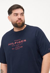 Granatowa bawełniana koszulka z krótkim rękawem z czerwoną nadrukowaną grafiką "TOMMY HILFIGER NEW YORK CITY Est. 1985" na przodzie. Okrągły dekolt.