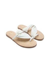 Chanclas blancas con una correa de tela anudada sobre una plantilla de ante marrón y suela de goma, con una textura suave y un diseño minimalista.