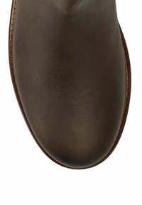 Bruine leren schoen met ronde neus en zichtbare stiksels langs de rand van de zool op een witte achtergrond.
