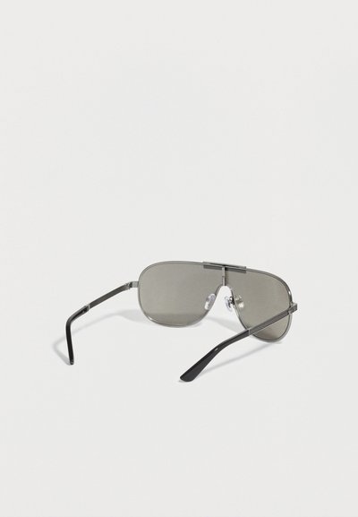 Γυαλιά ηλίου aviator με σκουρόχρωμους φακούς, λεπτό μεταλλικό πλαίσιο και μαύρα καμπυλωτά μπράτσα σε λευκό φόντο.