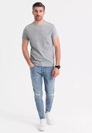 Gray cotton t-shirt with a crew neck and "Original" text on the chest, paired with light blue distressed jeans and white sneakers.