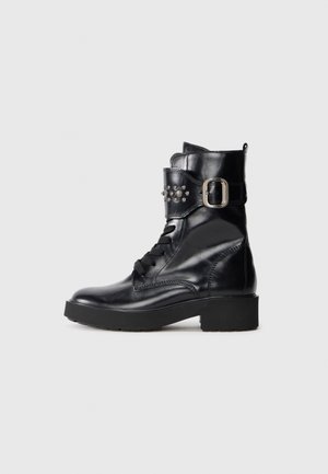 Black mid-calf leather combat boot with chunky heel, side buckle strap with metal studs, and front laces on a plain background.