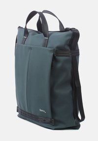 Donkergroene waterdichte tote bag met zwarte handvatten, ritsluiting, en een externe zak met verticale naden en een logo label.