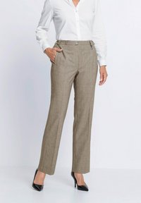 Bruine geruite broek met een getailleerde pasvorm, voorzien van zijzakken en een knoopsluiting, gecombineerd met een wit overhemd met knopen en zwarte hakken.