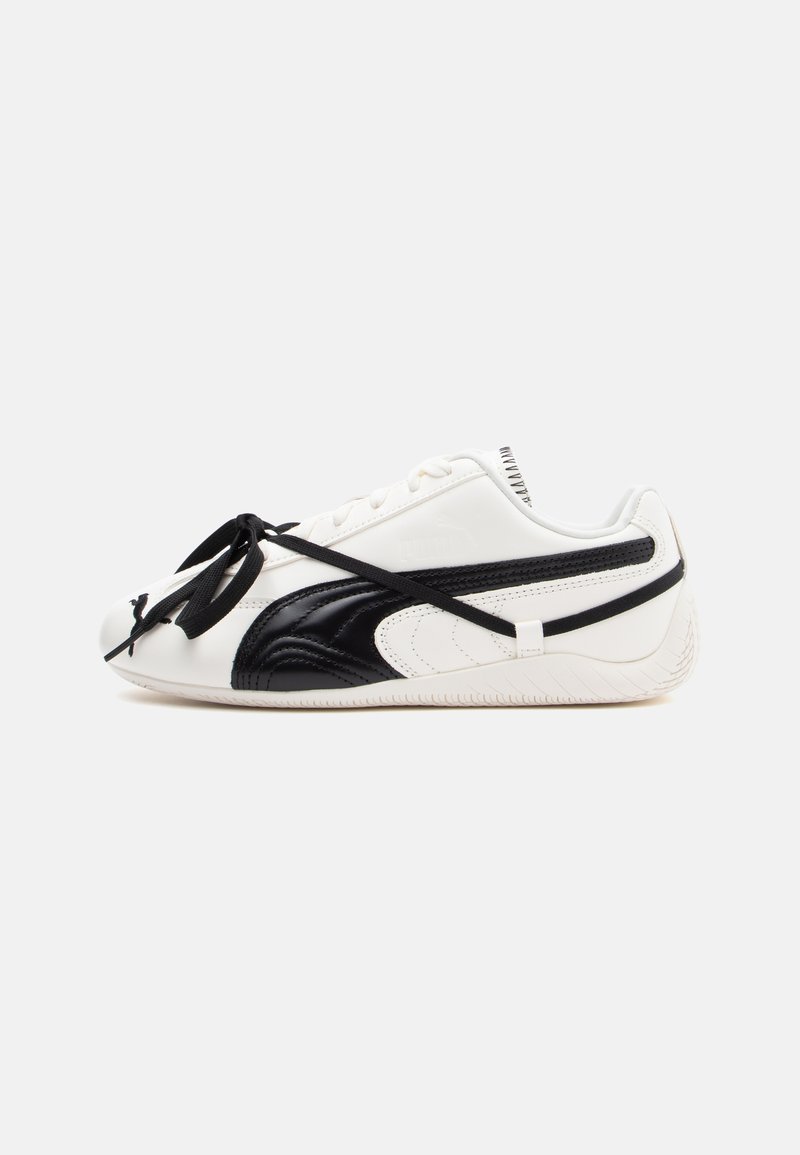 Valge ja must sneaker sileda nahkviimistlusega, ümmarguse ninaga, mustade paeltega ning tekstureeritud külgmiste aktsentidega. Logo nähtav küljes.