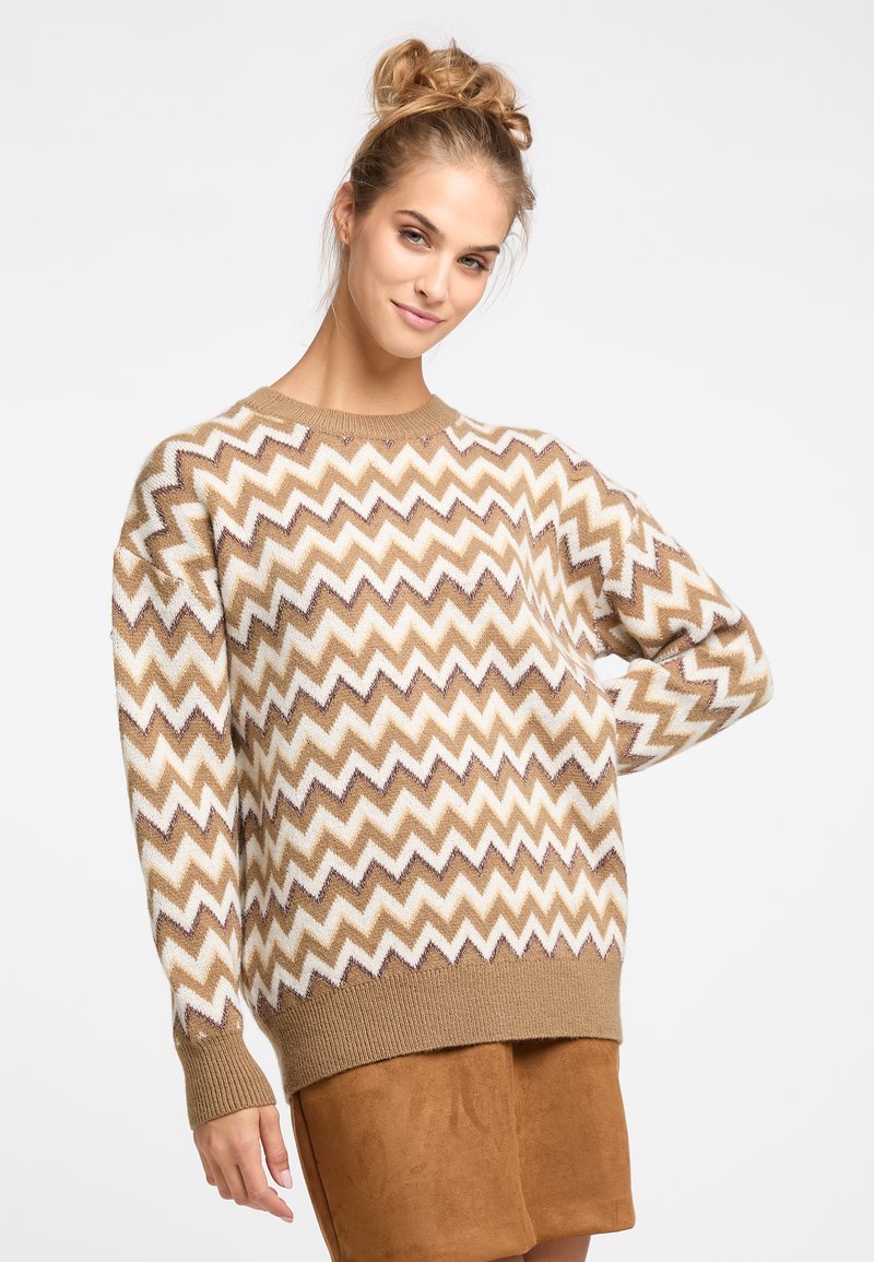 Pulover cu model zigzag maro și crem, cu gât rotund și manșete cu nervuri, purtat împreună cu o fustă din piele de căprioară maro.
