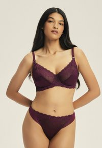 Burgunderfarbener Spitzen-BH und passende Bikinihöschen aus halbtransparentem Stoff, mit floralen Mustern, verstellbaren Trägern und welligen Rändern.