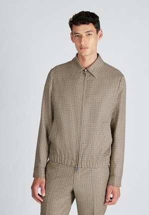 Brown and beige checkered jacket with a high collar, zip closure, elastic waist, and long sleeves; smooth fabric with a consistent pattern.