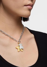 Collana in argento con ciondoli a forma di stella dorata e orsetto in argento. I ciondoli hanno un design giocoso con superfici lisce, sospesi dalla catena.