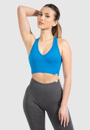 Soutien-gorge de sport cropped bleu à côtes avec un décolleté en V et de larges bretelles, associé à un legging gris taille haute avec une silhouette ajustée.