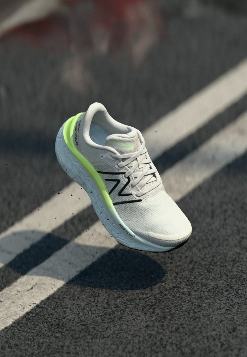 Sapatilha de corrida New Balance branca e verde neon no ar acima do asfalto, com marcas de faixa brancas.