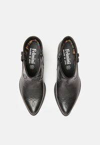 Botines de cuero negro hasta el tobillo con punta afilada, que presentan diseños en relieve en la parte superior, cierre con cremallera y forro de estampado colorido.