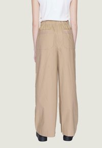 Pantaloni beige a gamba larga con elastico in vita, dotati di due tasche posteriori e realizzati in un tessuto leggero e morbido.