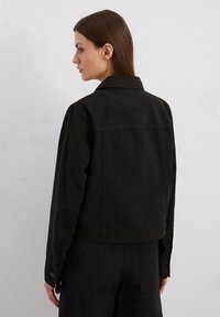 Zwarte denim jacket met een kraag, knoopmanchetten en een cropped ontwerp. Heeft eenvoudige stiksels en een gladde textuur.