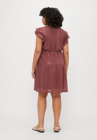 Raspberry-colored lace dress featuring short ruffled sleeves, a gathered waist, and a flared hemline with layered textures.