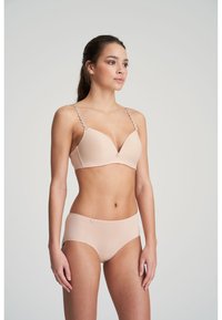 Light beige bra with a plunging neckline, featuring decorative circular straps, paired with matching seamless panties. Smooth texture throughout.