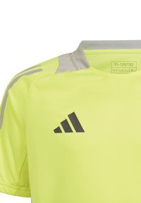 T-shirt de sport jaune fluo avec des accents gris et un logo noir. Il présente un col rond et un tissu qui évacue l'humidité.