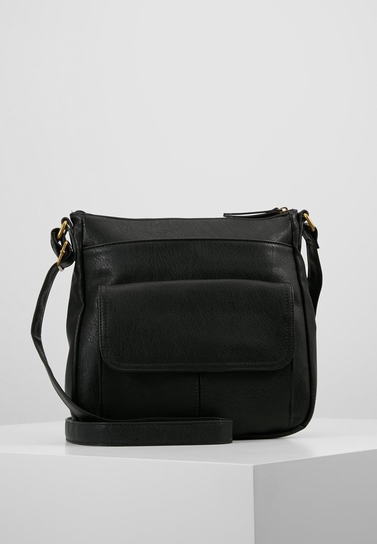 Svart läder crossbody-väska med framficka, justerbar rem och guldfärgad hårdvara på en vit yta med ljusgrå bakgrund.